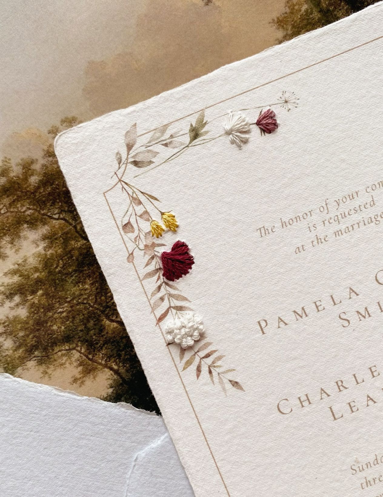 Handmade paper wedding invitation with embroidered accents